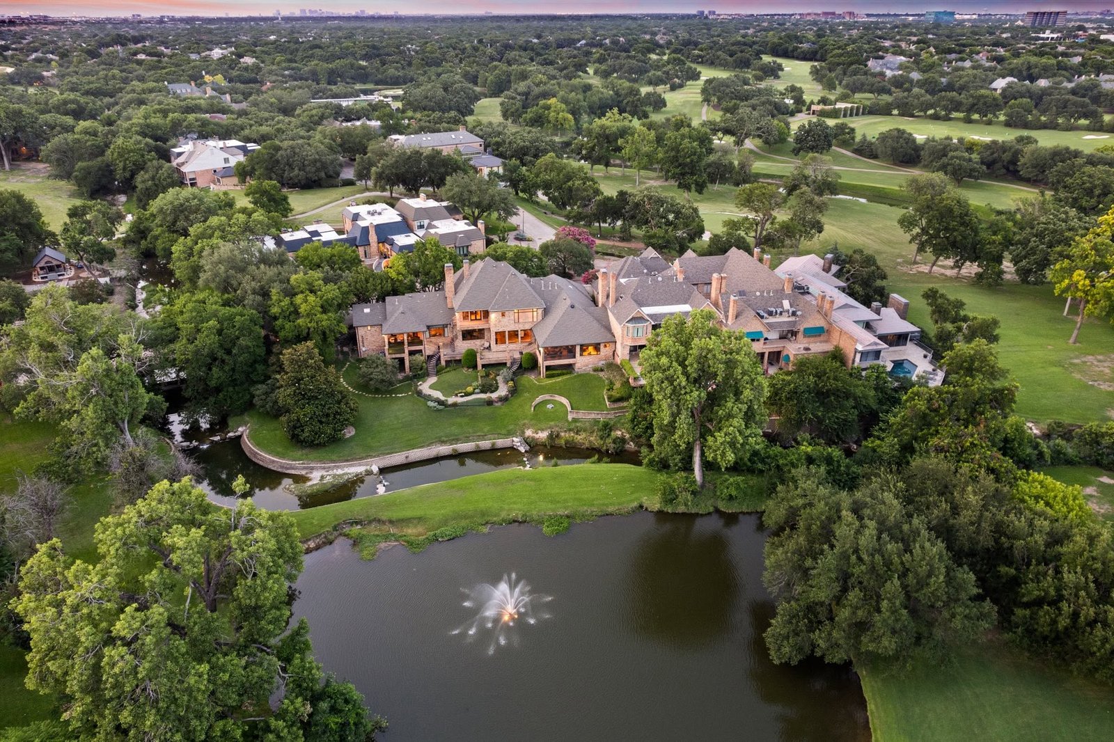 Aerial view of an estate framed by trees, gardens and a pond