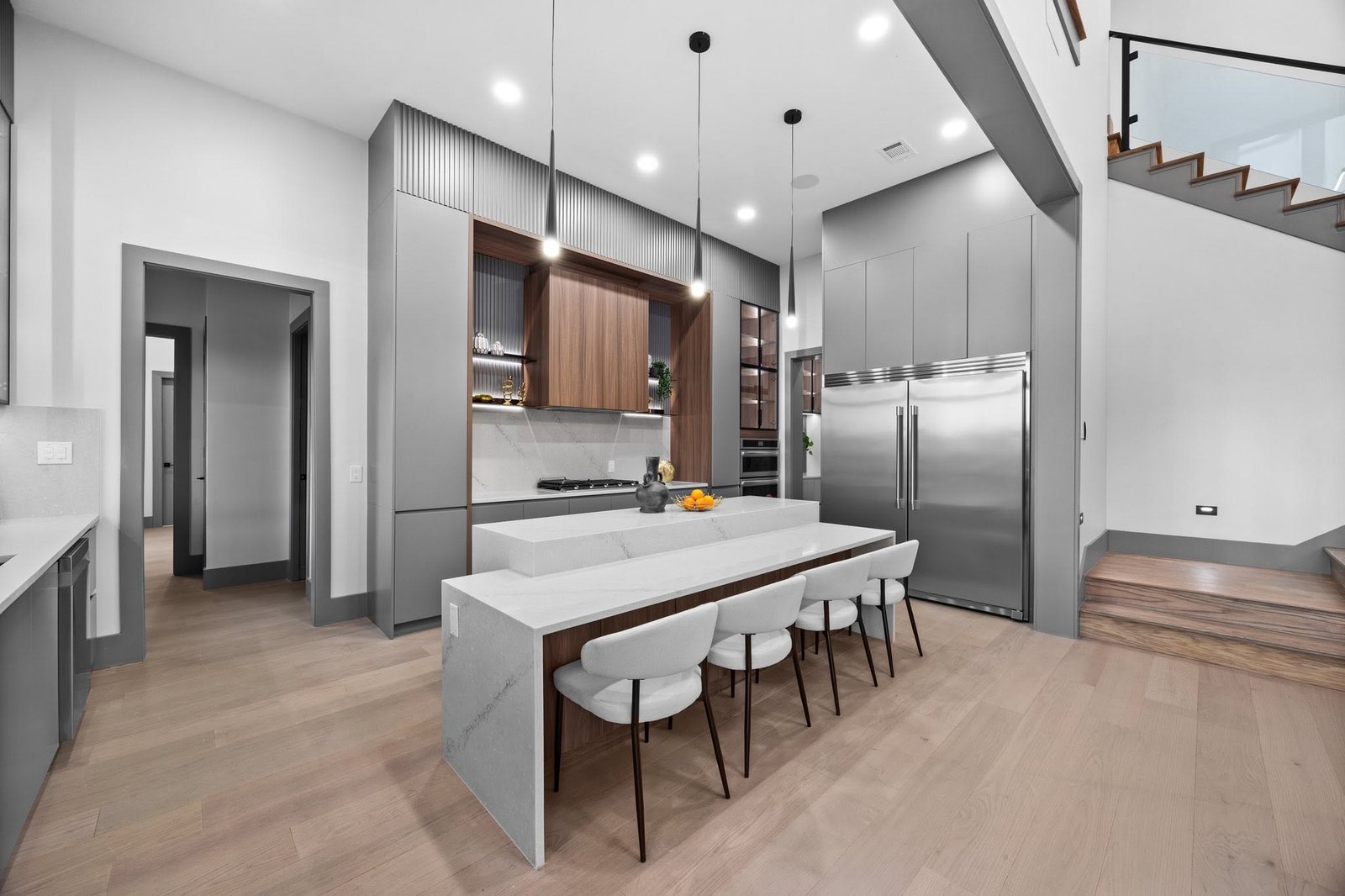 Contemporary kitchen with wood cabinetry, a waterfall island and sculptural lighting